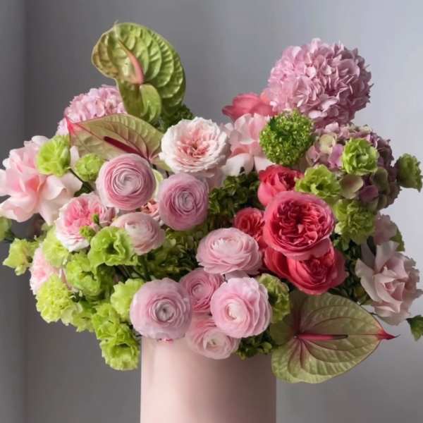 Pink and green floral arrangement in a blush vase