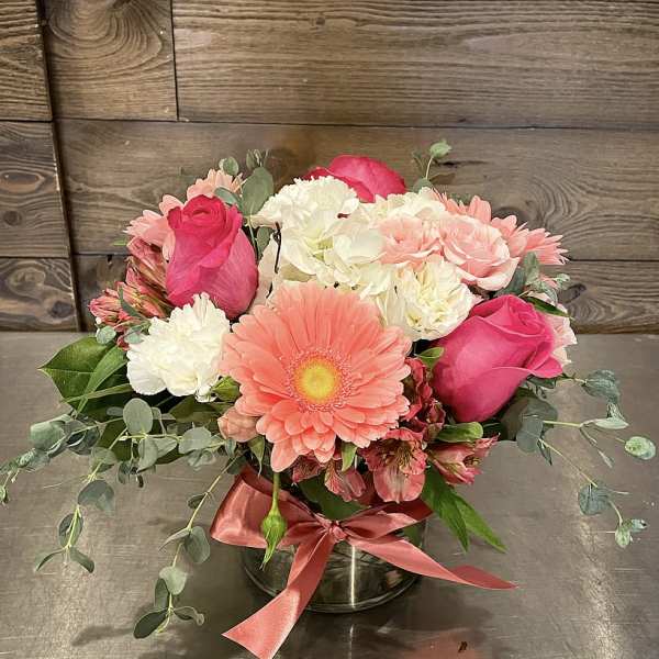 Pink and white mixed flower arrangement in a glass vase with ribbon