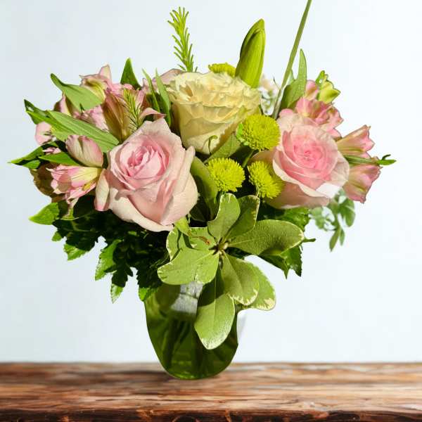 Pink roses and cream flowers in a glass vase