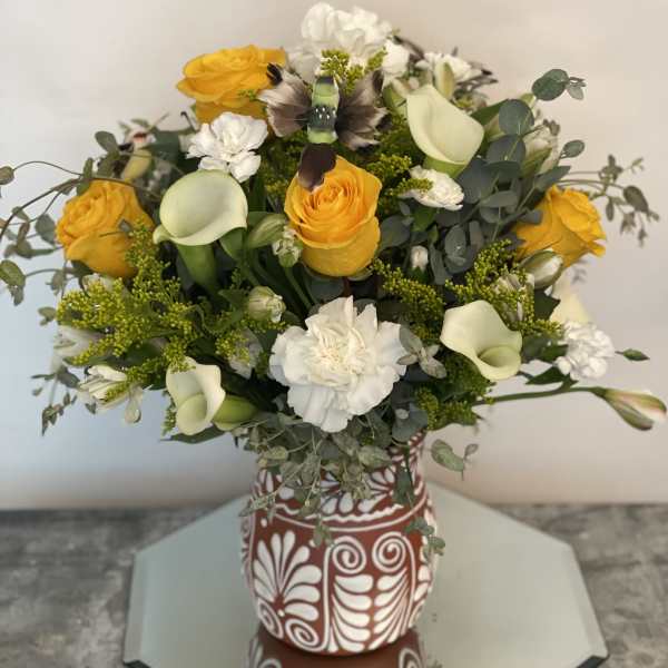 Bouquet of yellow roses, white calla lilies, and white carnations in a patterned vase