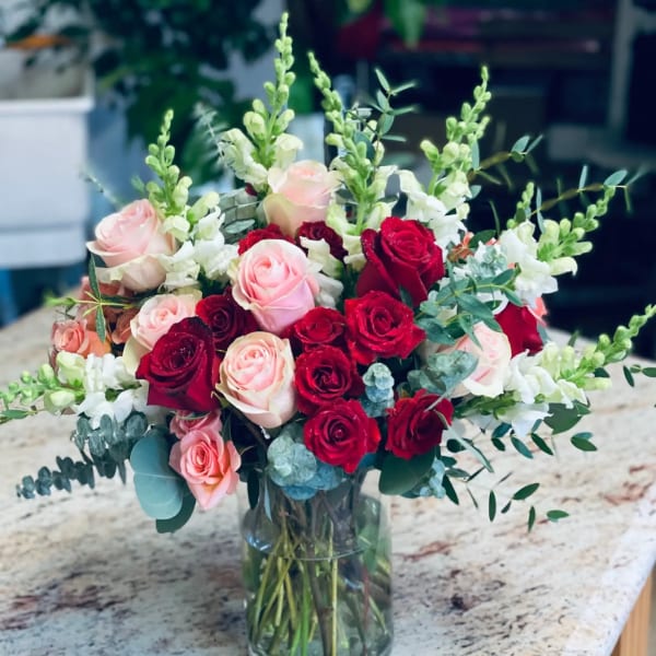 Bouquet of red and blush roses in a clear glass vase