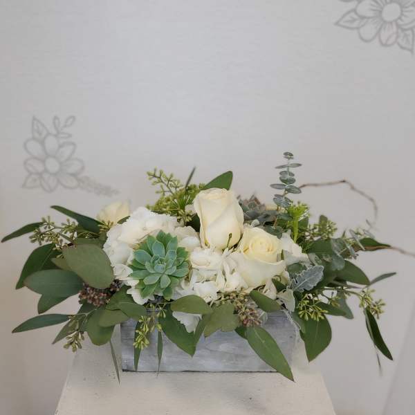 White roses and succulents arranged in a low rectangular container