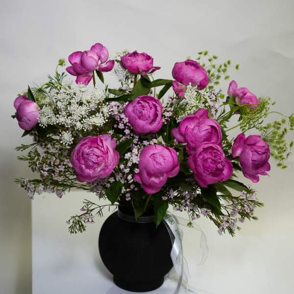 Pink peony bouquet in a black vase with white filler flowers