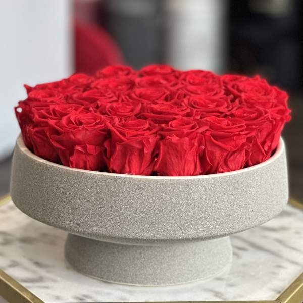 Round box filled with red roses on a pedestal stand
