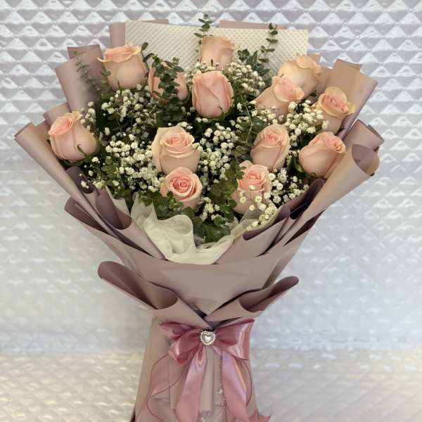 Bouquet of pale pink roses with baby's breath in mauve wrapping