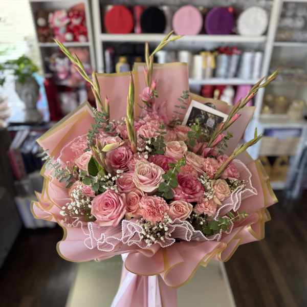 Pink rose bouquet with carnations and tall buds in pastel wrapping