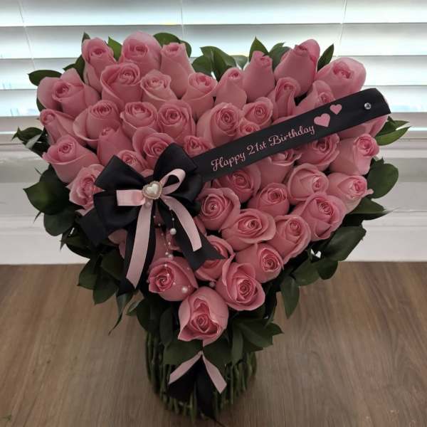 Heart-shaped bouquet of pink roses with a birthday ribbon