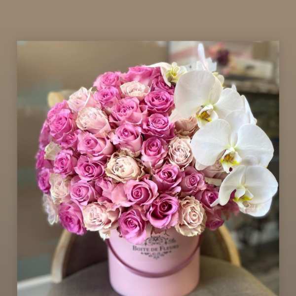 Pink roses and white orchids arranged in a pink hat box