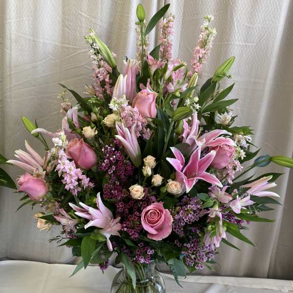 Pink lilies and roses arranged in a clear glass vase