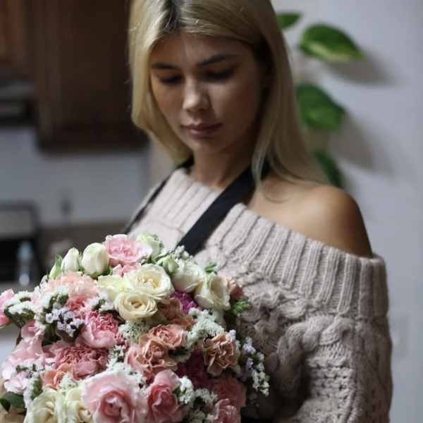 Woman holding a large bouquet of pink and white roses
