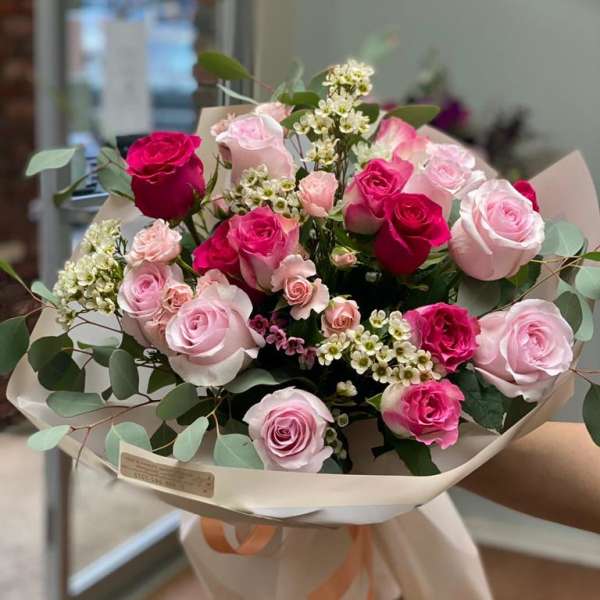 Bouquet of pink and red roses wrapped in cream paper