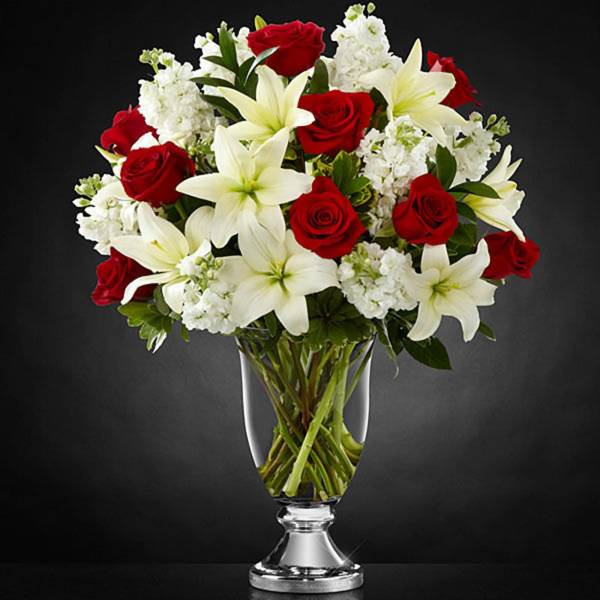 Red roses and white lilies arranged in a clear glass vase