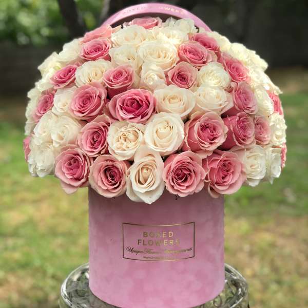 Pink and white roses arranged in a round pink hat box