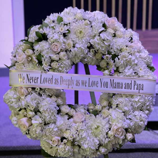 White floral wreath on an easel with a memorial ribbon