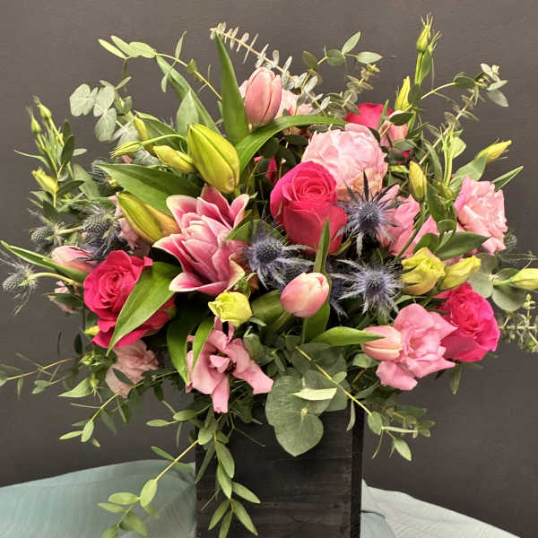 Mixed pink bouquet with roses and lilies in a dark wooden box