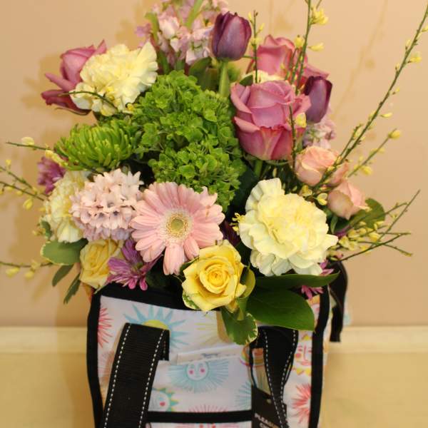 Mixed pastel flower arrangement in a patterned tote bag