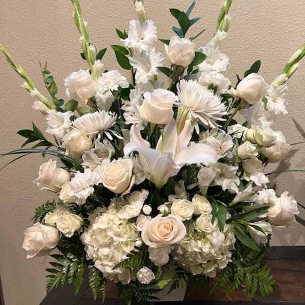 Tall white floral arrangement with roses, lilies, and gladiolus