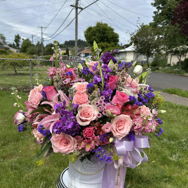 Large pink and purple flower arrangement in a white hatbox with lavender ribbon