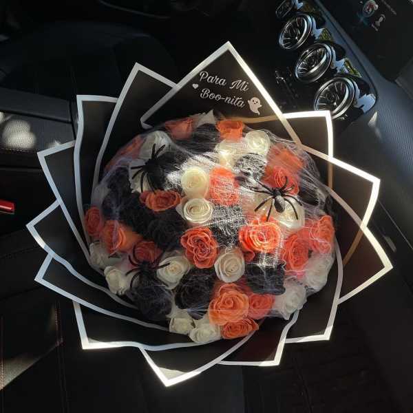 Bouquet of orange, white, and black roses with spider decorations