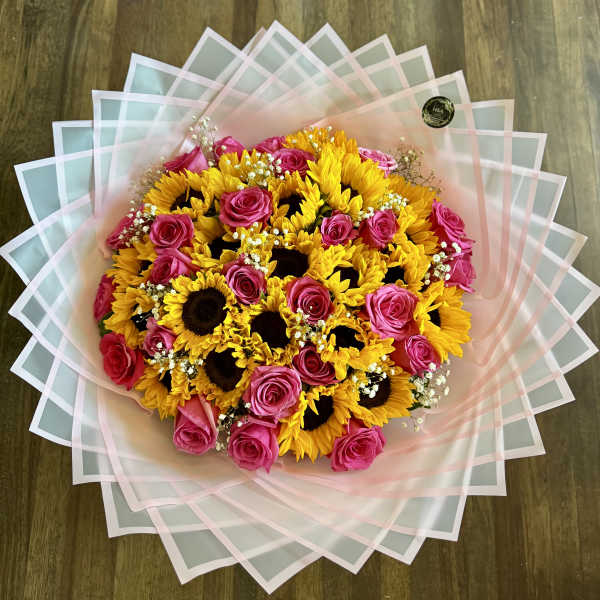 Bouquet of pink roses and yellow sunflowers wrapped in pastel paper