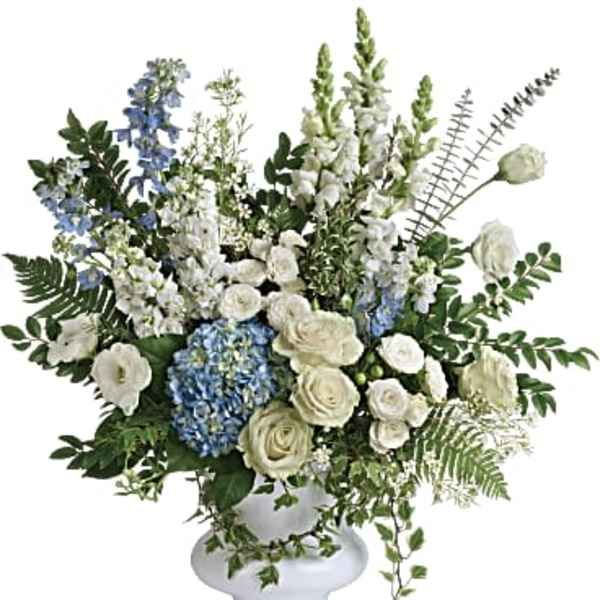 White and blue floral arrangement in a white pedestal vase
