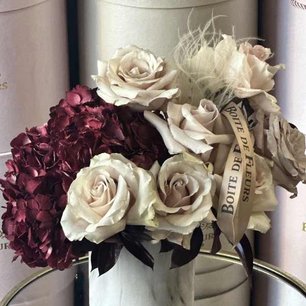 Bouquet of cream roses and burgundy hydrangeas in a round box