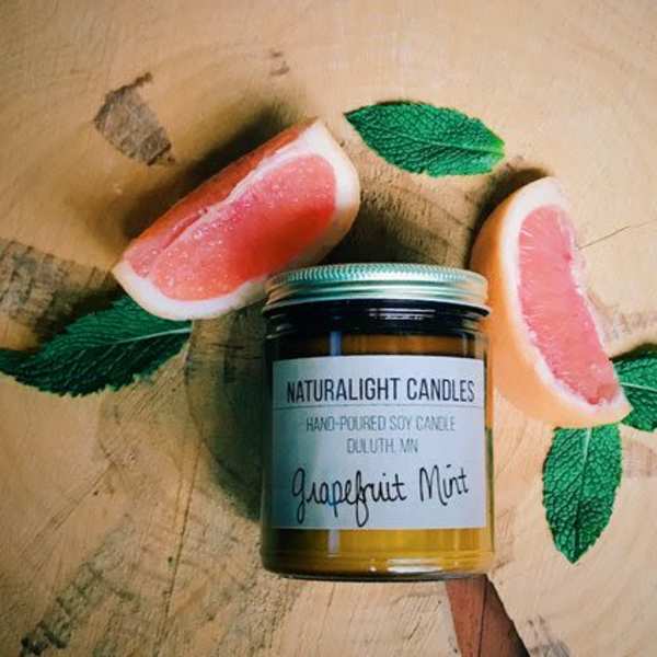 Jar candle with grapefruit slices and mint leaves on a wooden surface