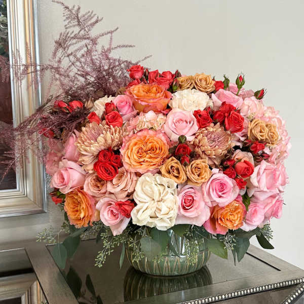 Large bouquet of pink, red, and peach roses in a glass vase