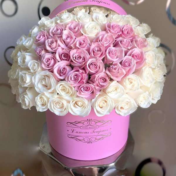 Round pink hatbox filled with tightly packed pink and white roses