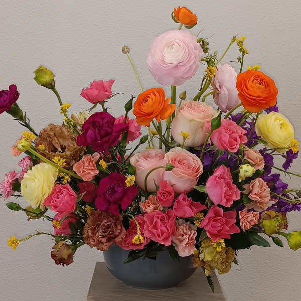 Mixed bouquet in a dark vase with pink, orange, yellow, and purple flowers