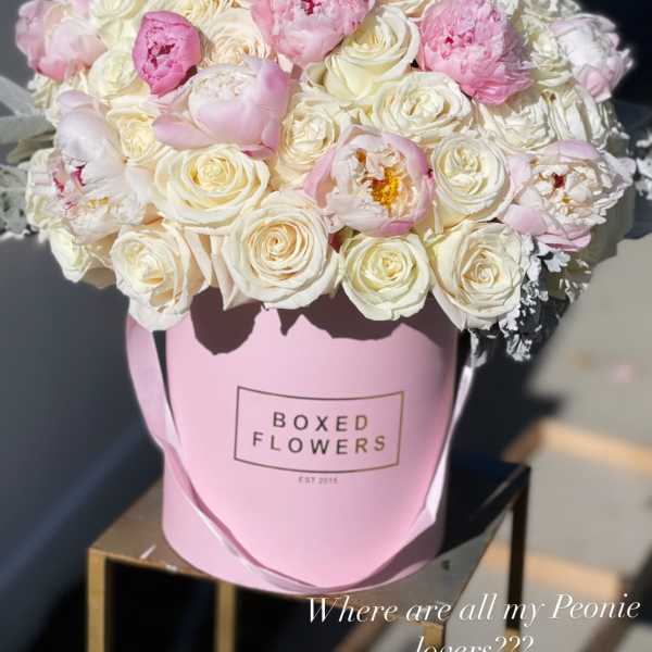 Pink and white bouquet of peonies and roses in a pink box