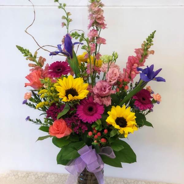 Colorful mixed bouquet in a glass vase with a purple ribbon