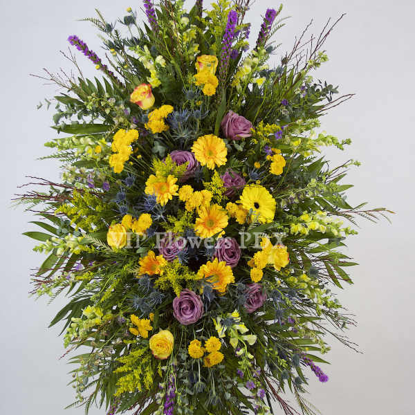 Large standing spray of yellow, purple, and green flowers on an easel