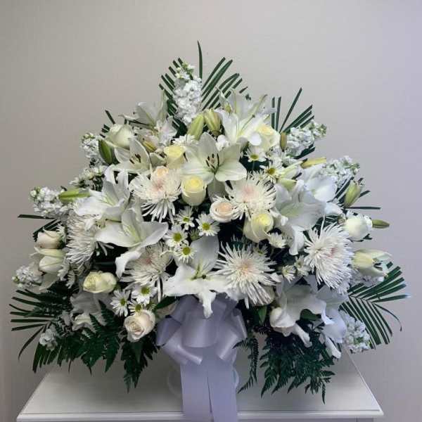 Large white floral spray with lilies and daisies, tied with a lavender ribbon