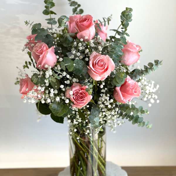 Pink roses in a clear glass vase with white filler flowers