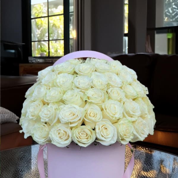 Bouquet of white roses in a pink round box with ribbon handles