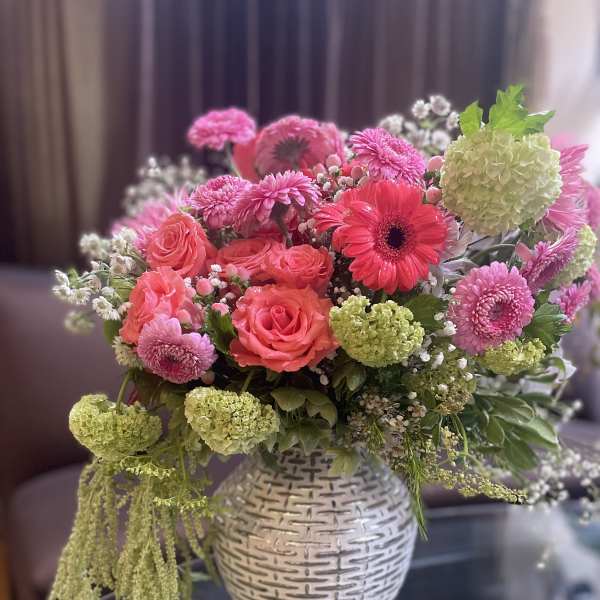Pink and coral mixed bouquet in a white textured vase