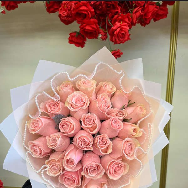Bouquet of pink roses wrapped in pale paper with pearl trim
