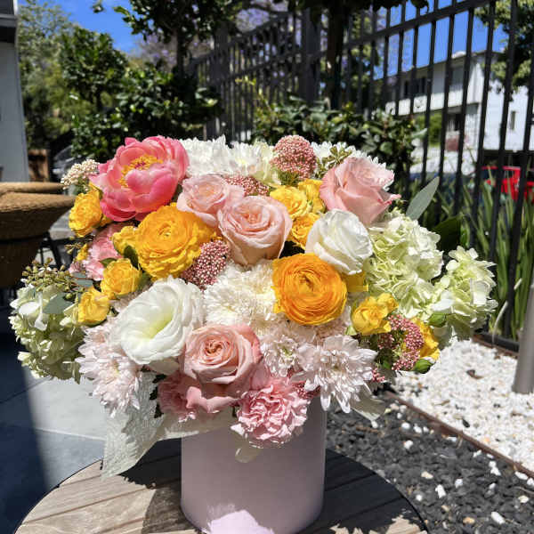 Mixed bouquet of pink, white, and yellow flowers in a pink vase