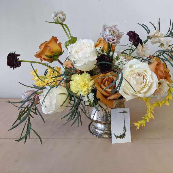 Mixed bouquet of roses, peonies, and carnations in a silver vase