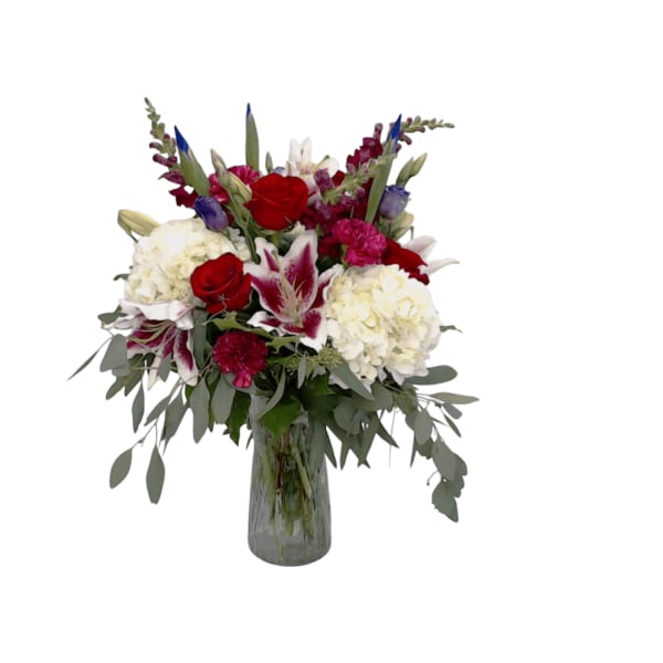 Mixed bouquet of red, white, and pink flowers in a glass vase