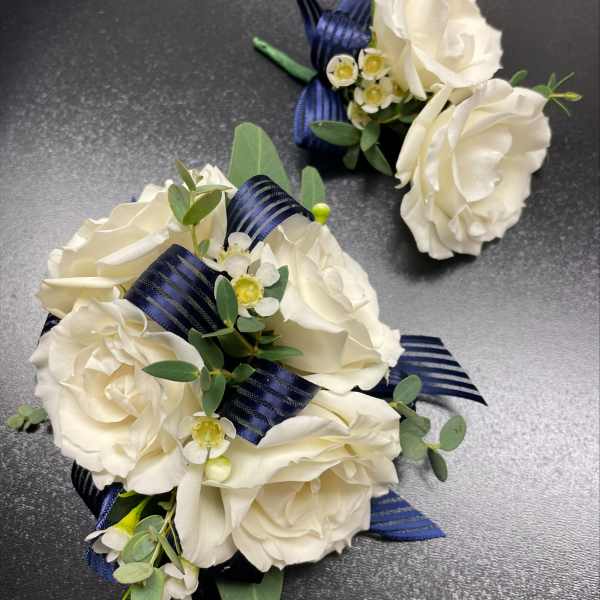 White rose corsages with navy ribbon and small white filler flowers