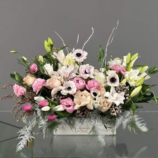 Pink and white floral arrangement in a white box with lilies and roses