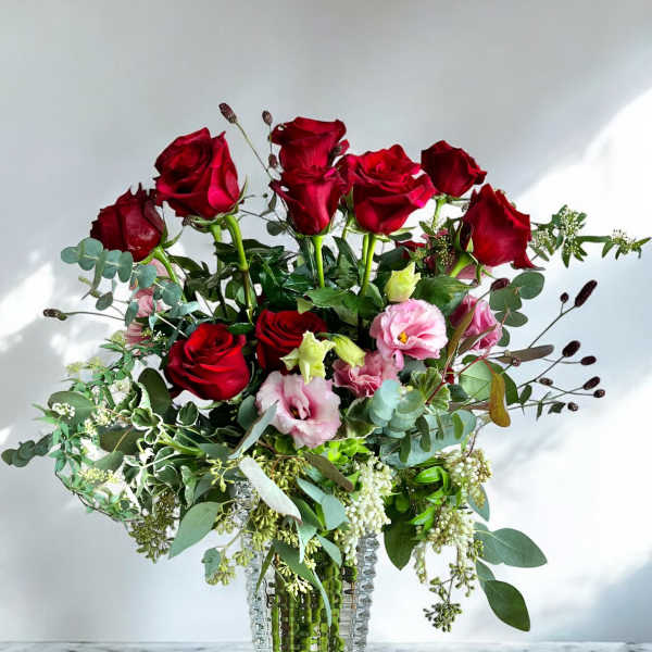 Red roses and pink lisianthus in a clear glass vase