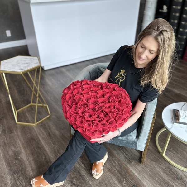 Woman holding a large heart-shaped bouquet of red roses