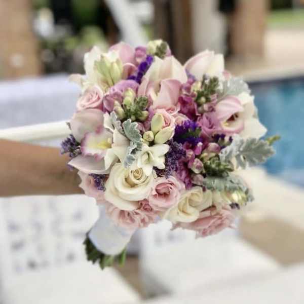 Handheld bouquet of pink and white flowers with purple accents