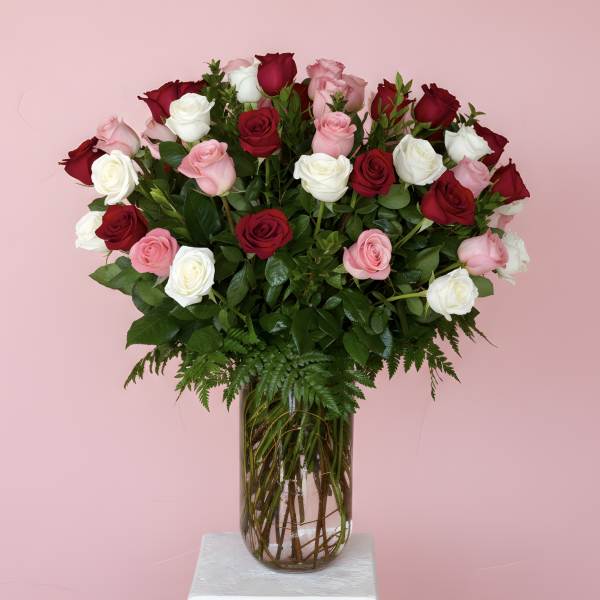 Bouquet of red, pink, and white roses in a clear glass vase