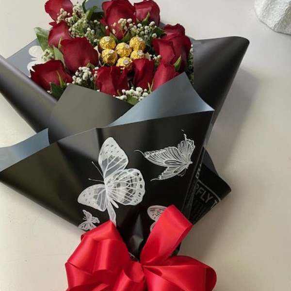 Bouquet of red roses wrapped in black paper with a red ribbon