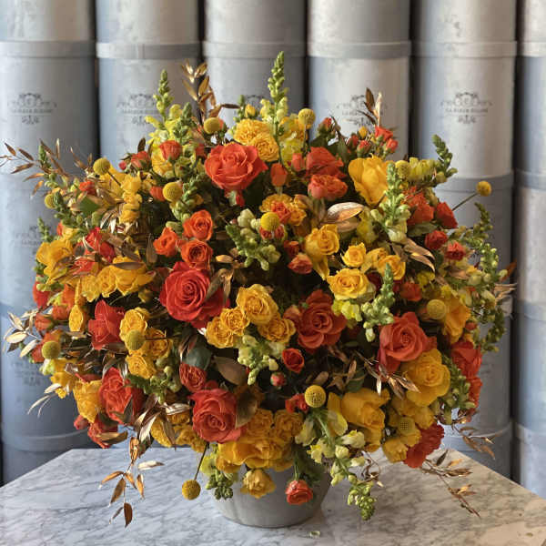 Large bouquet of yellow and orange roses in a gray vase