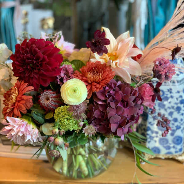 Mixed bouquet in a glass vase with burgundy, peach, and cream blooms